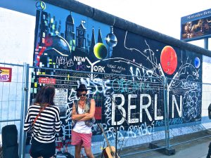 Man Wearing Black Waistcoat and White Tank Tops Standing Near a Mural By Tomer Levi Forex